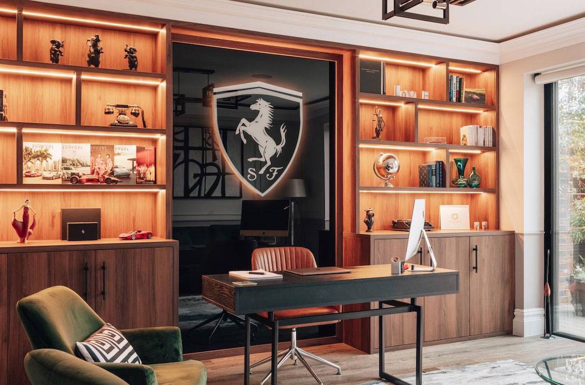 Executive home office featuring a Ferrari shield logo backboard, dark wood desk, and built-in LED display shelves, ideal for corporate and tech ad shoots, Love Locations.
