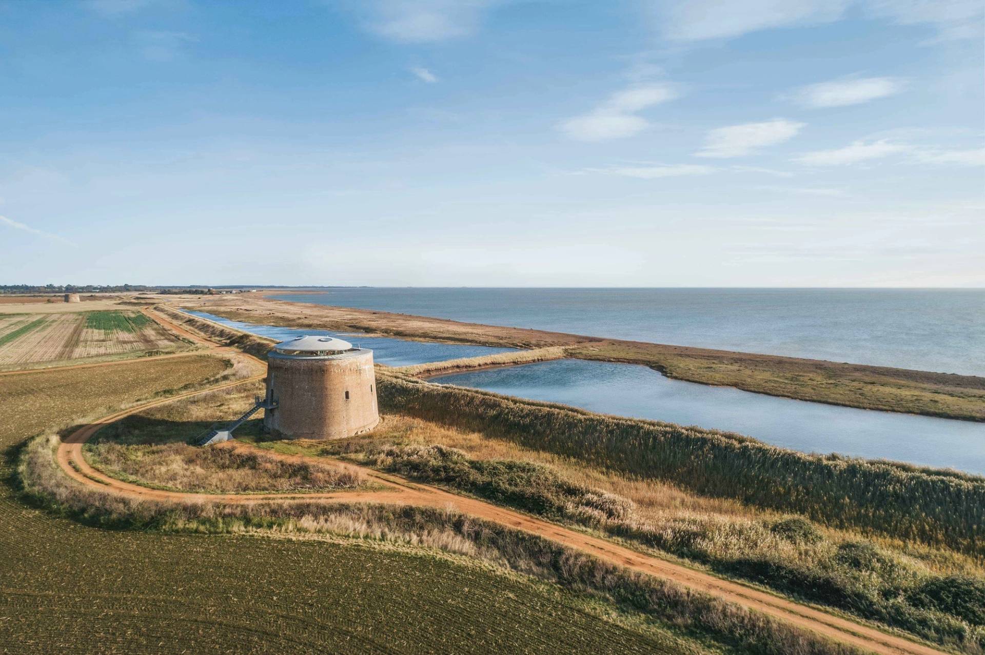 Scenic countryside landscape view featuring a coastal Martello tower and salt marsh waterways by Love Locations.