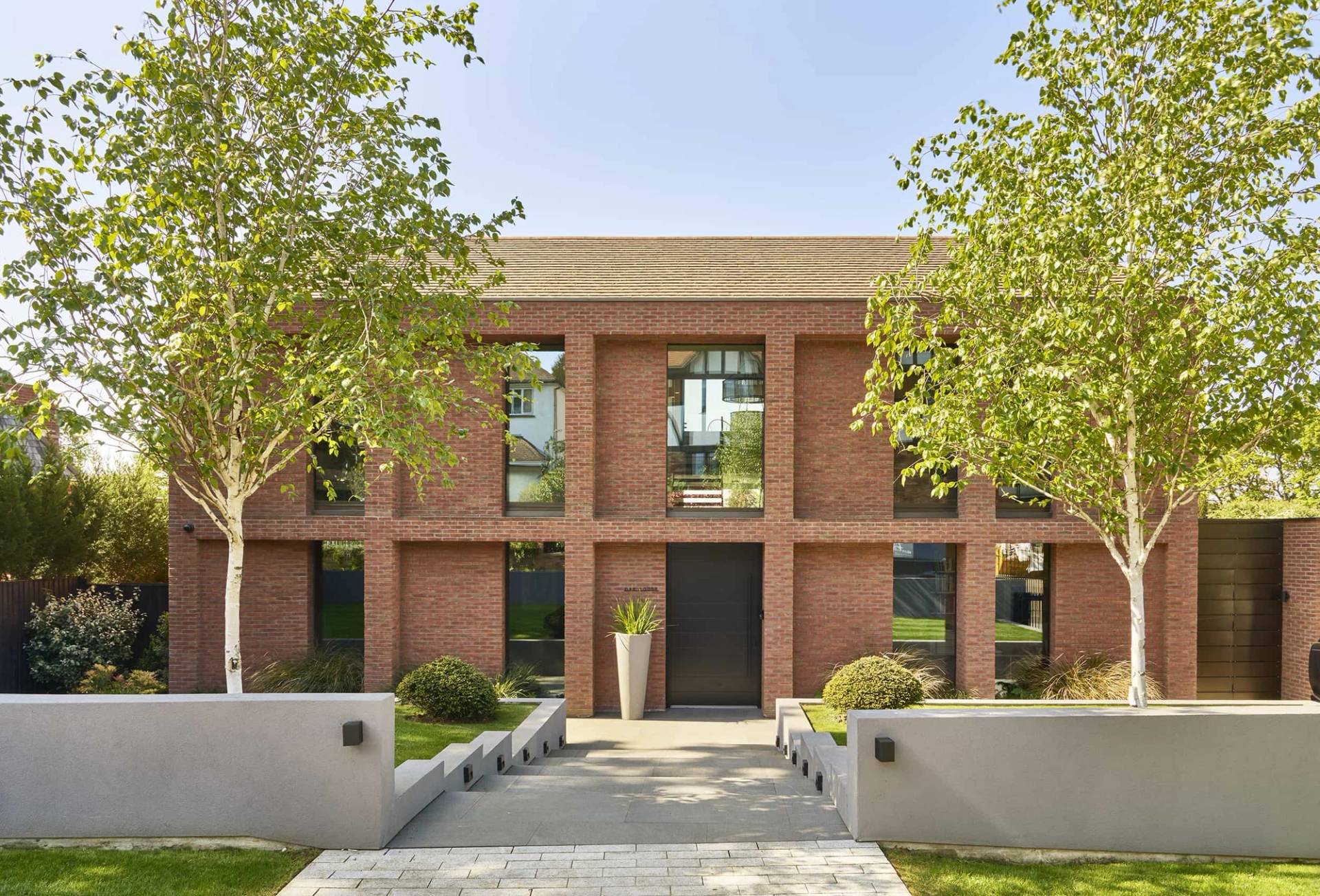 Symmetric modern red brick mansion front exterior with a paved entrance walkway in Chislehurst, BR7, Love Locations.