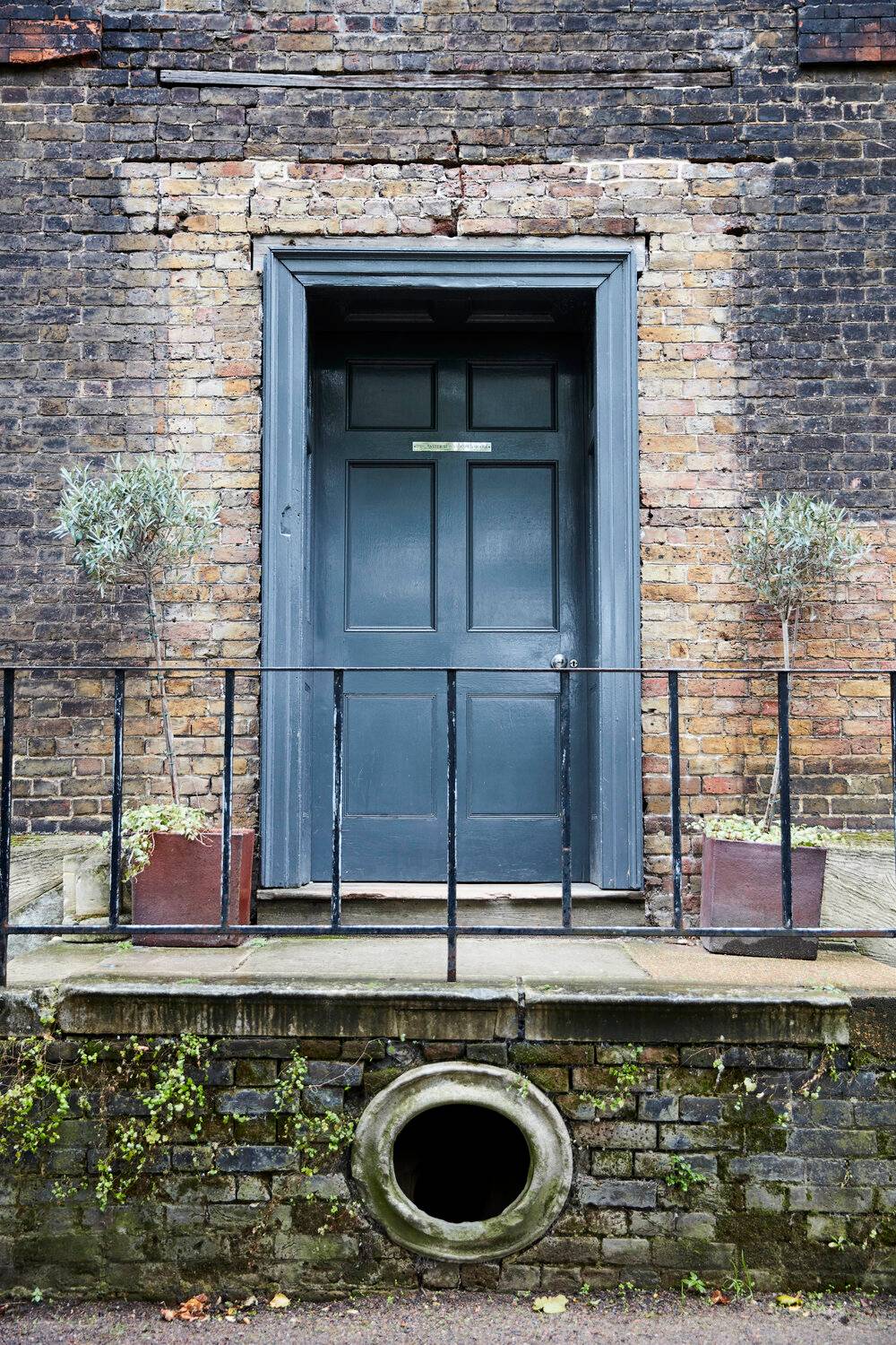 Close-up of a dark blue Georgian entrance door with iron railings and stone steps in South East London, Love Locations SE8.