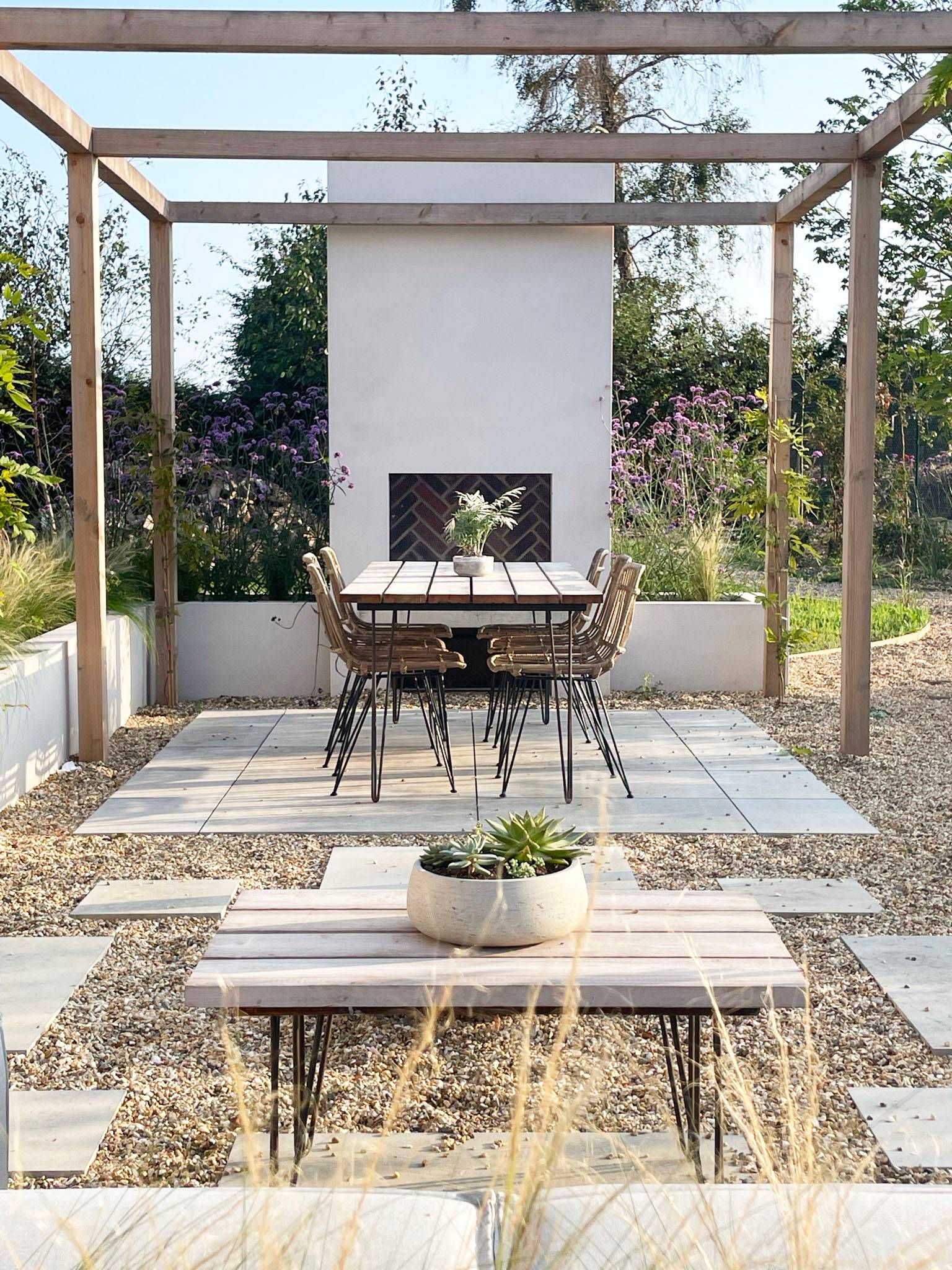 Outdoor dining patio featuring a pergola fireplace, stone gravel seating area, and outdoor dining set in a Chichester location home, ideal for garden furniture lookbooks, Love Locations.
