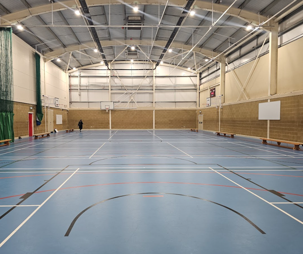 Expansive indoor academy sports hall location with line markings for basketball, netball, and badminton, managed by Love Locations.