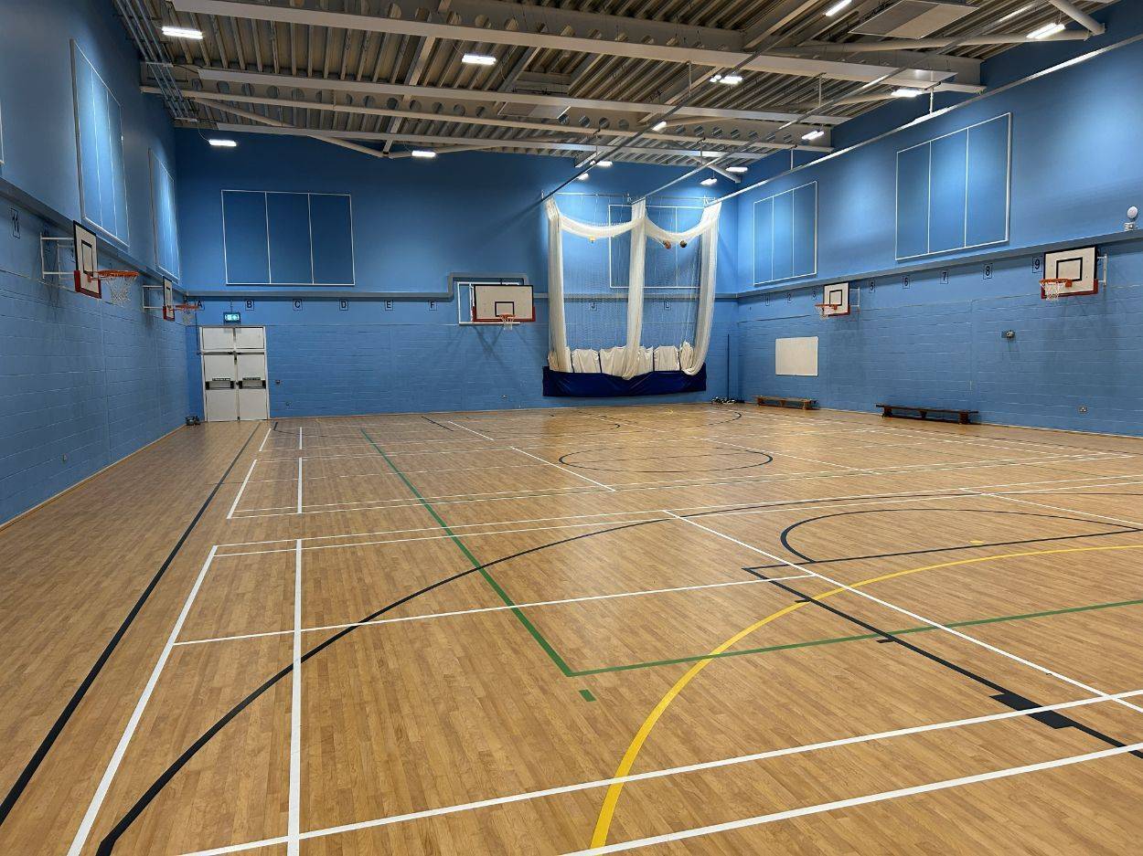 Multi-use indoor sports hall filming space with marked game lines and overhead rafters in Sittingbourne Kent from Love Locations.