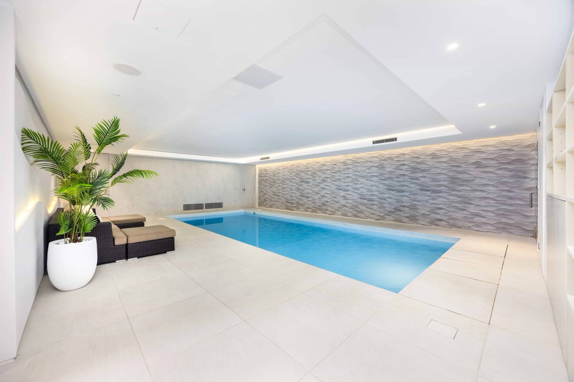Indoor swimming pool view looking across clear blue water towards luxury lounge seating, Love Locations WD7.
