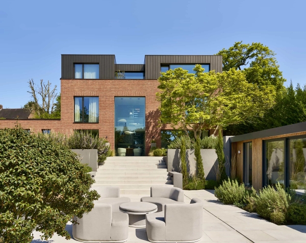 Stunning contemporary brick architectural house rear facade with landscaped stone terraces, exclusive to Love Locations.