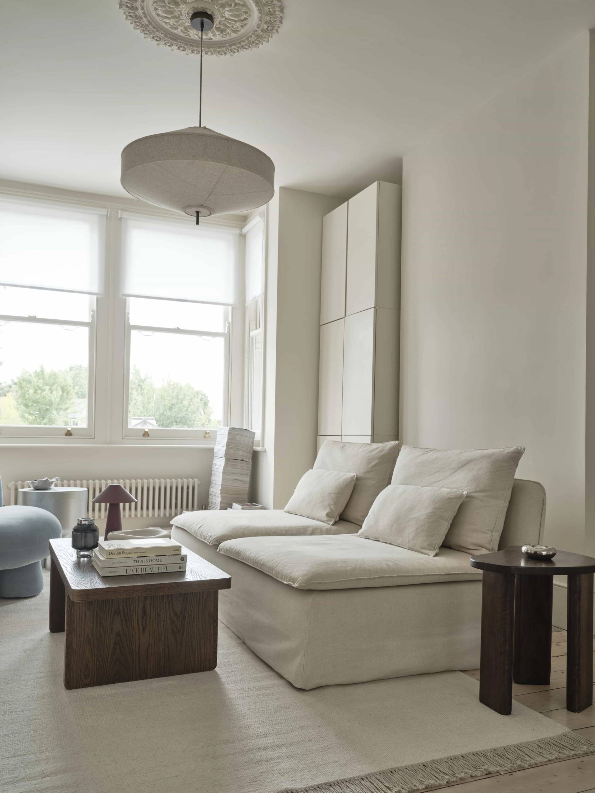 Low-profile cream sectional sofa set against a dark timber coffee table and beige walls, ideal for homeware ads, Love Locations E4.