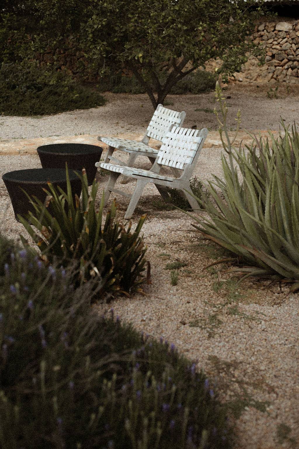 Rustic garden seating corner with white wooden chairs set in a gravel courtyard, Love Locations 07630.