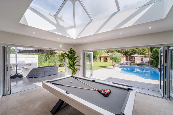 Pool table area looking through wide open bi-fold doors to an outdoor swimming pool, Love Locations RM11.