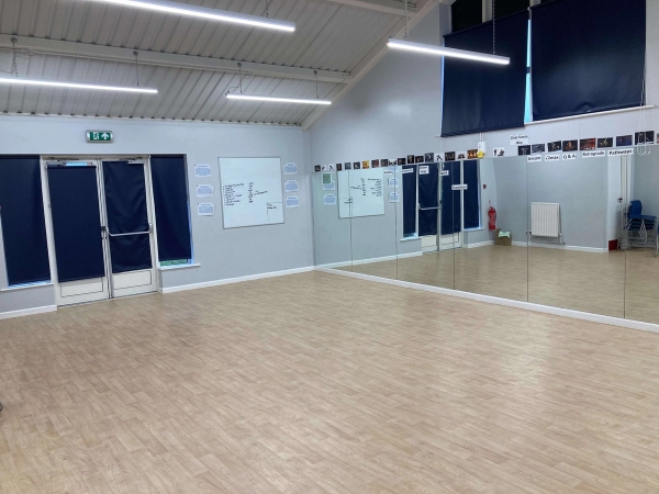 Love Locations dance studio shoot location CM1: Bright performing arts studio with a large wall mirror, professional wood flooring, and modern lighting, ideal for music videos and choreography training.