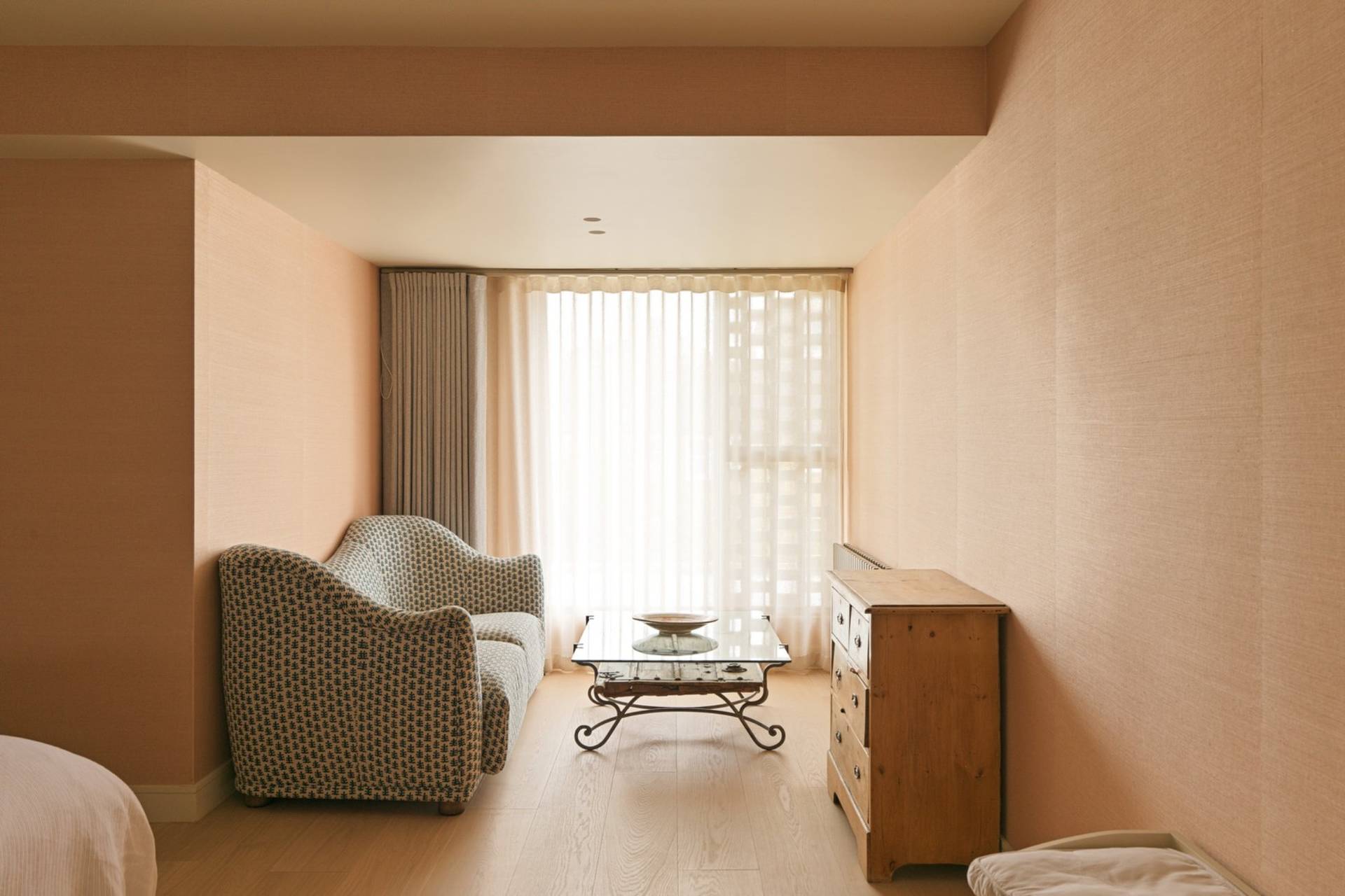 Stylish lounge corner in a master suite with a textured armchair, side table, and warm plaster wall finish by Love Locations.