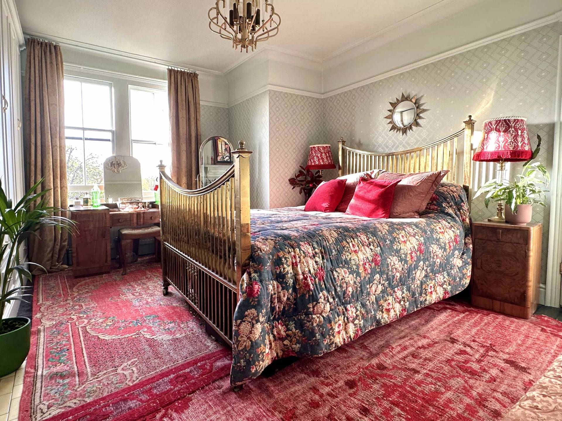 Bright Edwardian bedroom with brass bed frame, red bedding, and oriental area rug, Love Locations N13.