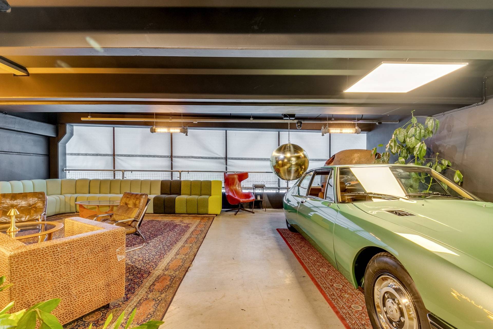 Wide car showroom and lounge shoot space with a classic green coupe and gold disco ball in Brentford TW8 via Love Locations.