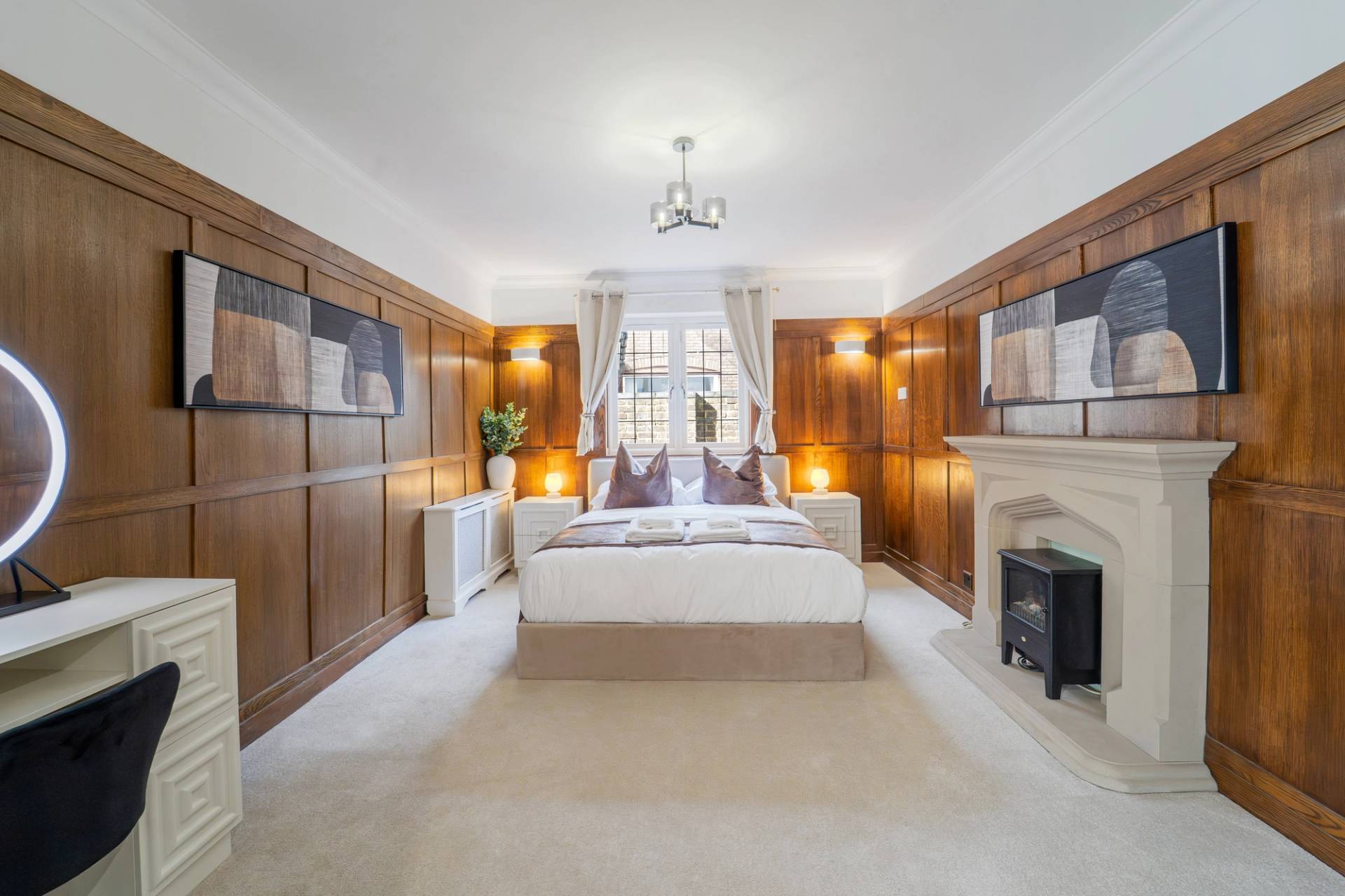 Luxury master bedroom suite with rich wood panelled walls, fireplace hearth, and neutral carpet, Love Locations RM11.