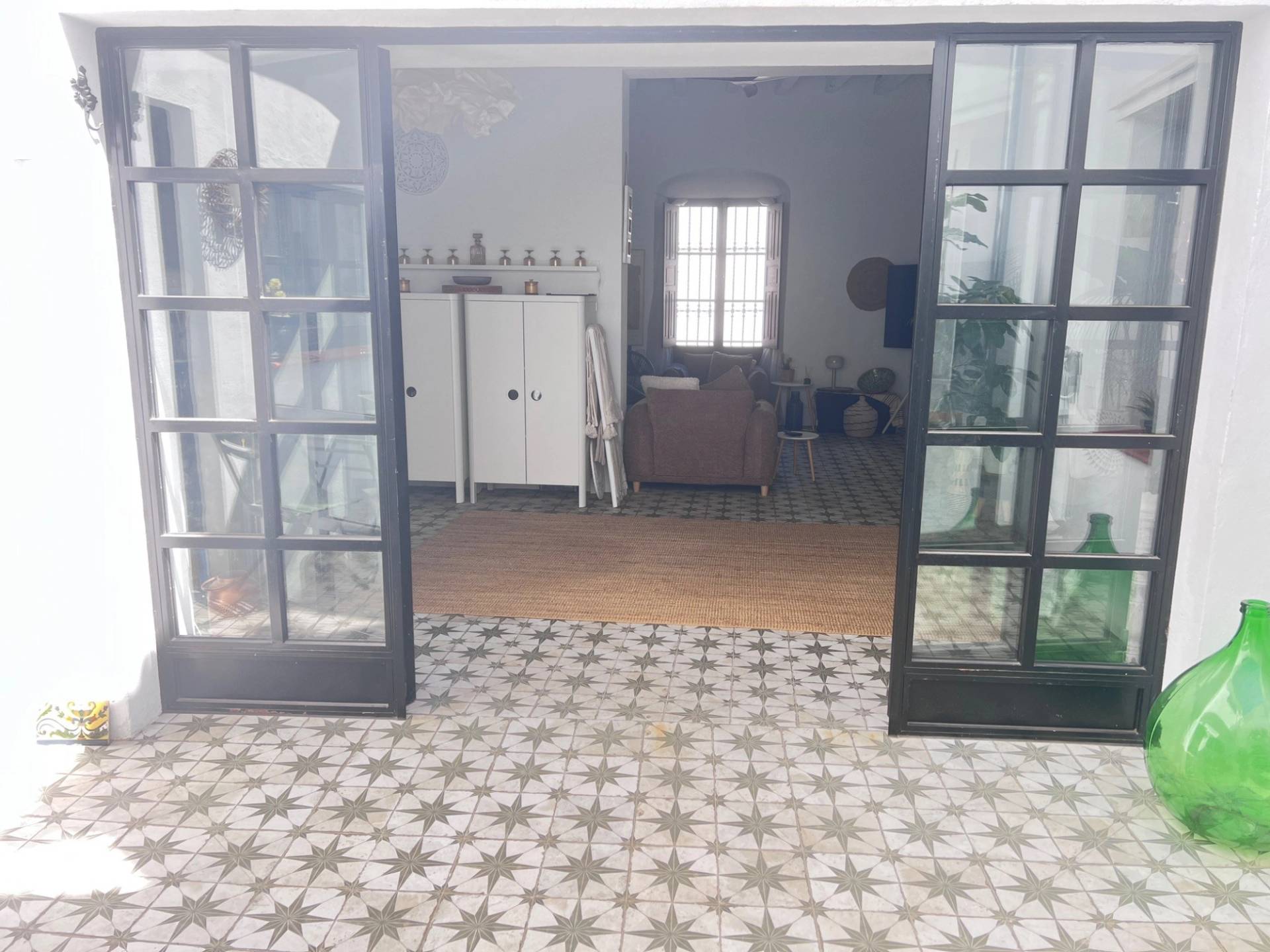 Open courtyard doors leading into a light-filled living area in Jimena de la Frontera from Love Locations, featuring black grid glass French doors.