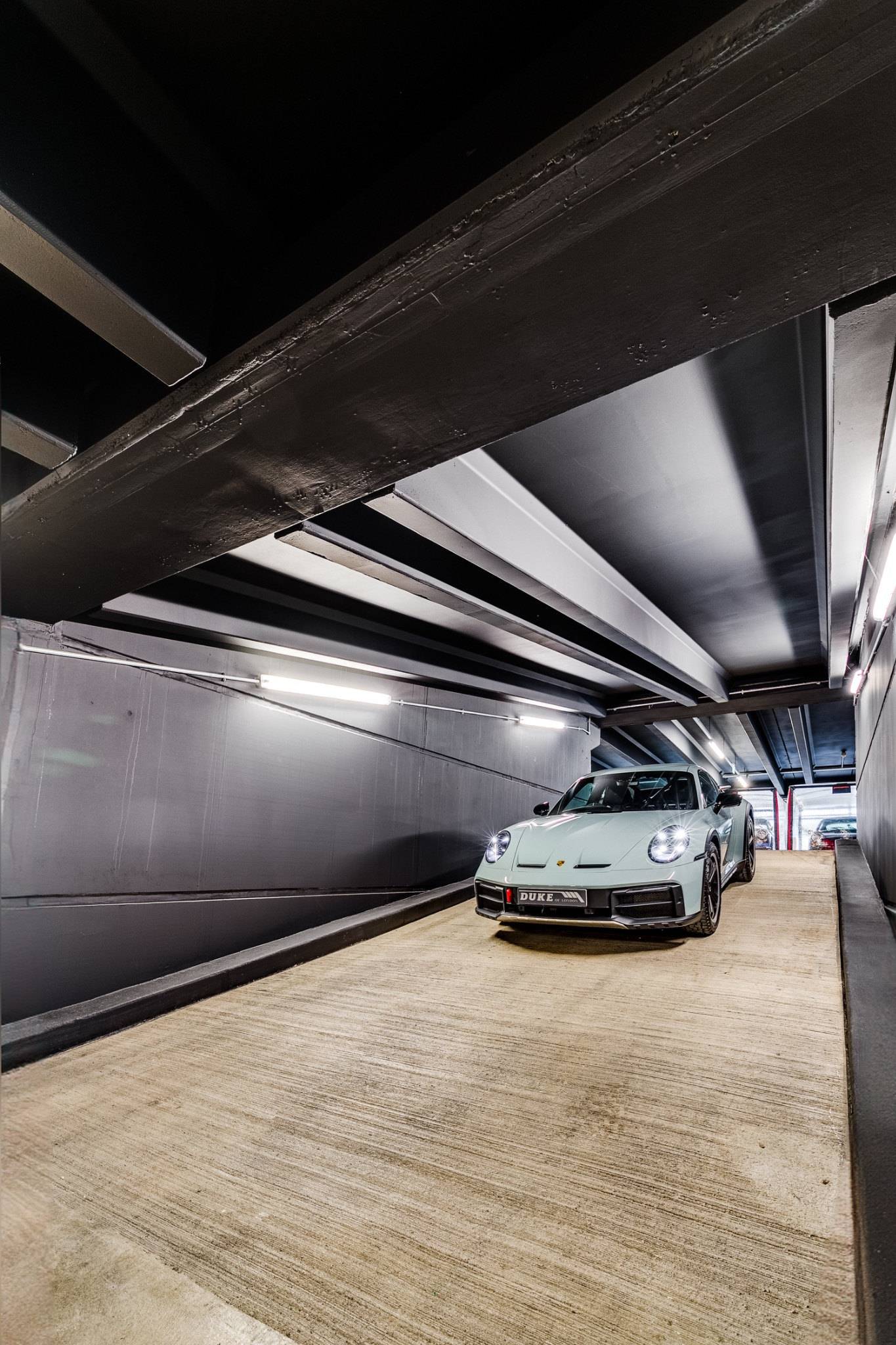 Modern Porsche sports car parked on polished wood flooring inside a black-walled studio space in Brentford from Love Locations.