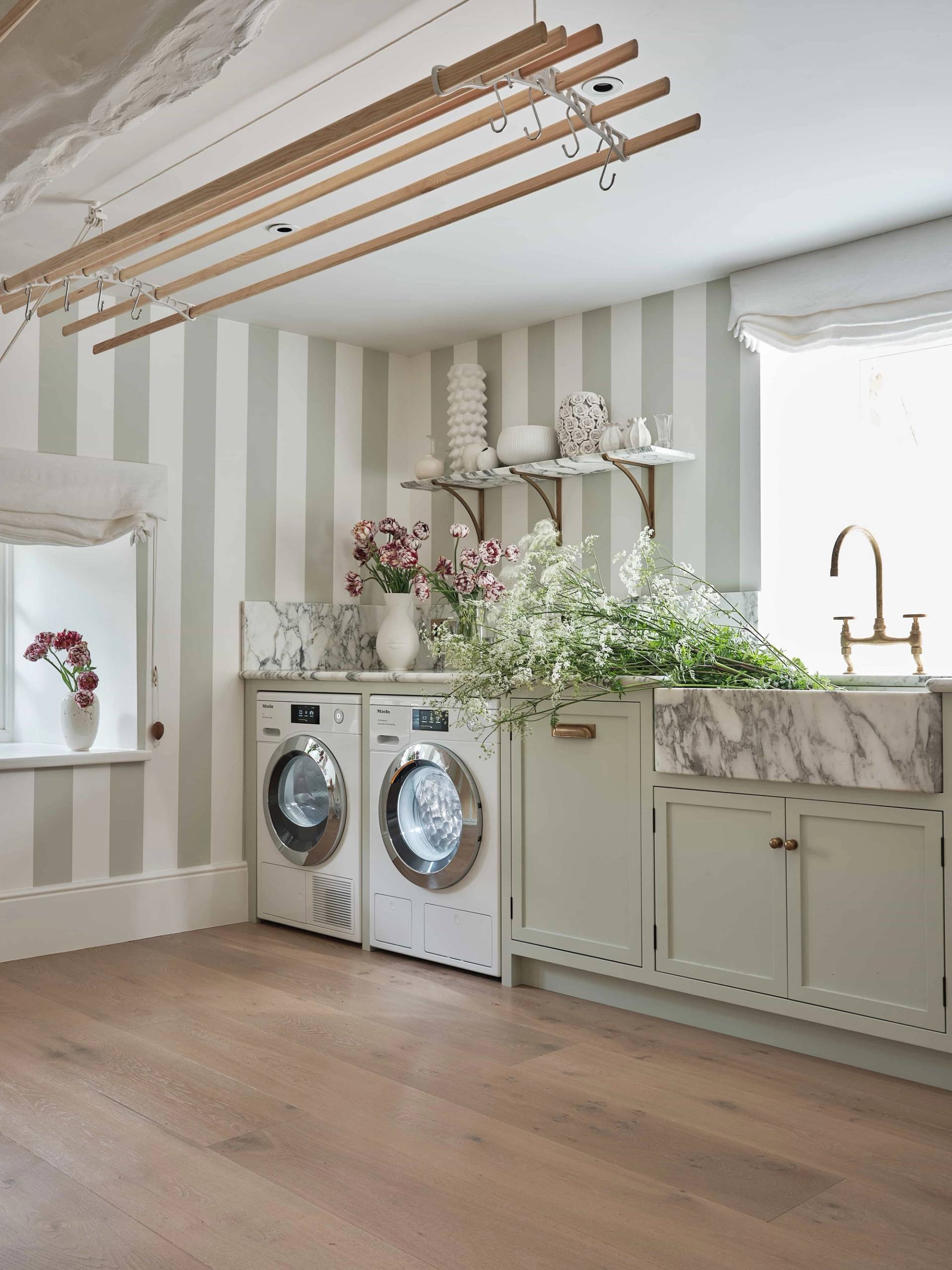 Country house utility laundry room featuring striped wall wallpaper, green cabinetry, Belfast sink, and drying rack, perfect for domestic product campaigns, Love Locations.