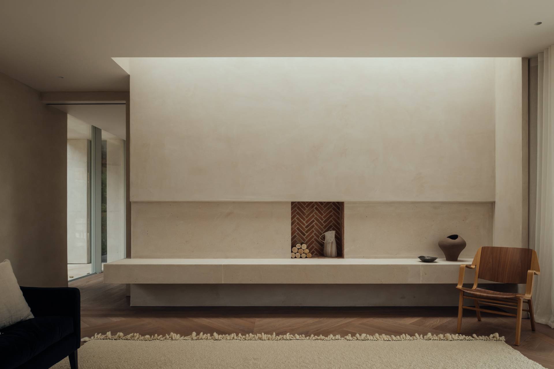 Minimalist plaster feature wall with an integrated low-profile stone bench hearth and recessed lighting, perfect for high-fashion editorial backdrops, Love Locations.