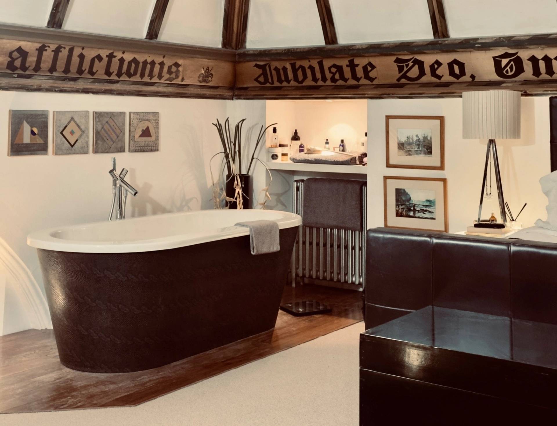 Unique bathroom location featuring a freestanding dark clawfoot bathtub set beneath pitched chapel roof beams in Oval SE5 from Love Locations.