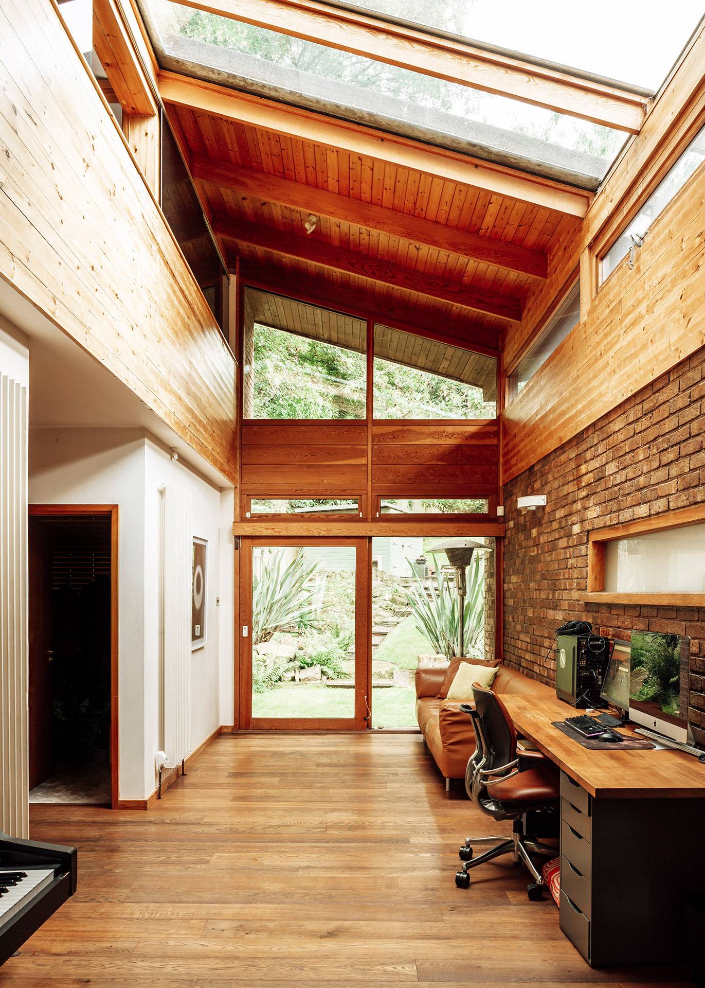 Mid-century home office and study space framed by exposed brick walls and massive glass windows looking into woodland, Love Locations BR1.
