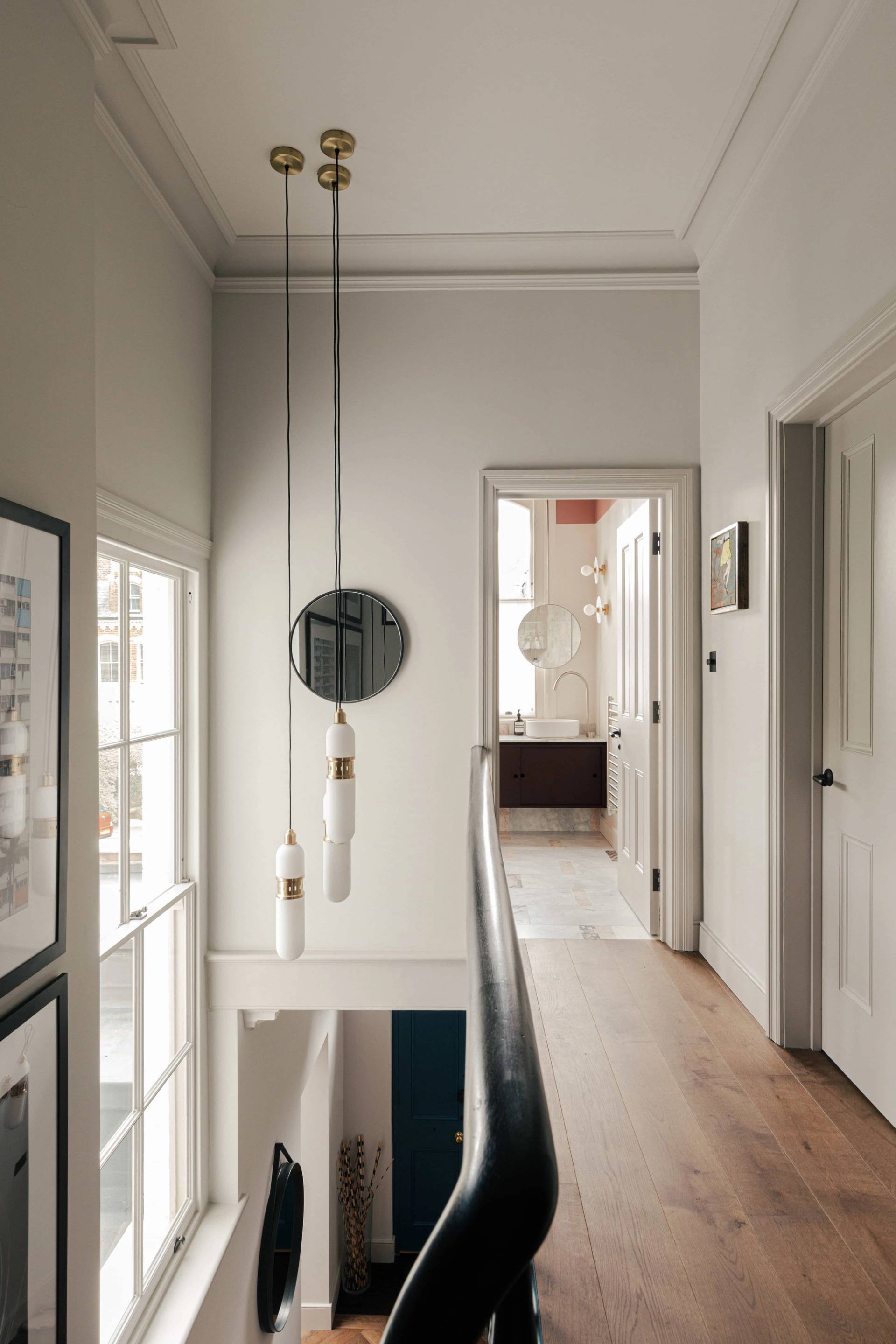 Upper hallway landing view looking down past hanging glass pendant lights and black balustrades, Love Locations.