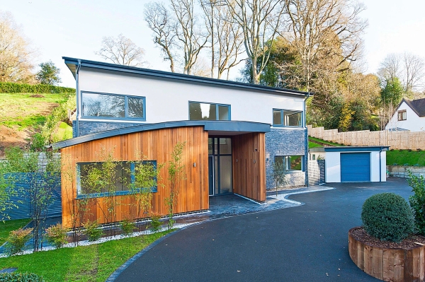 Front driveway approach of a modern architectural home combining warm cedar wood cladding and dark grey stone tiles, Love Locations.