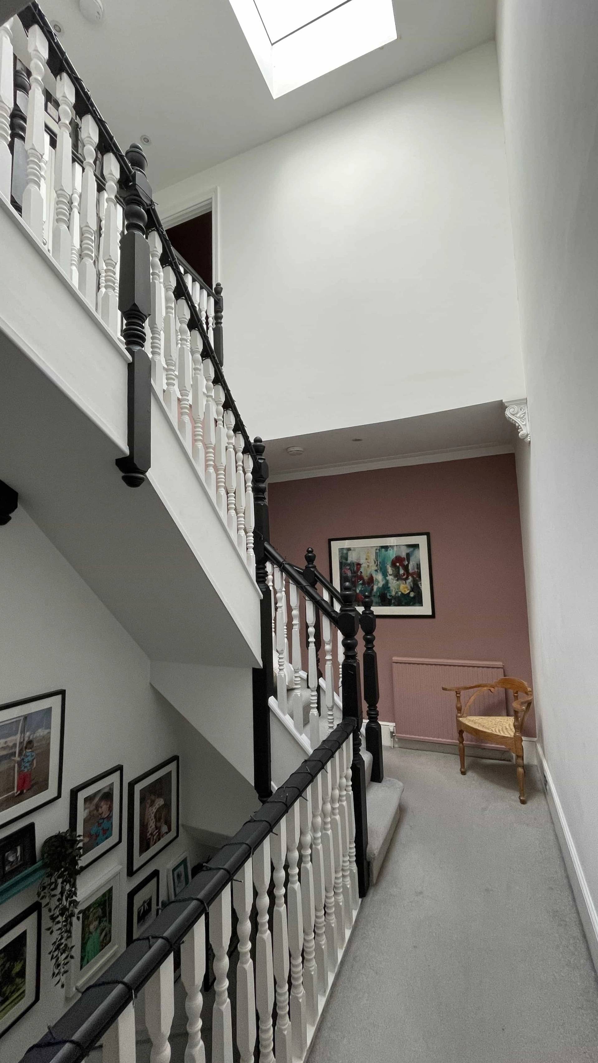 Staircase landing transition with black turned balusters, grey carpet runner, and dusty pink painted walls, Love Locations Ealing Common.