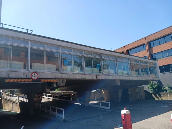 Brutalist concrete pillars and underpass film location in Watford WD18 available through Love Locations, showing an elevated architectural design against a blue sky.