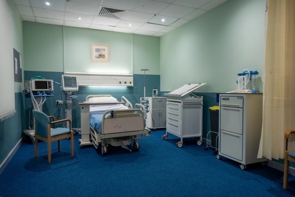 Private hospital ward room with adjustable bed, overbed table, and medical storage units, Love Locations UB4.