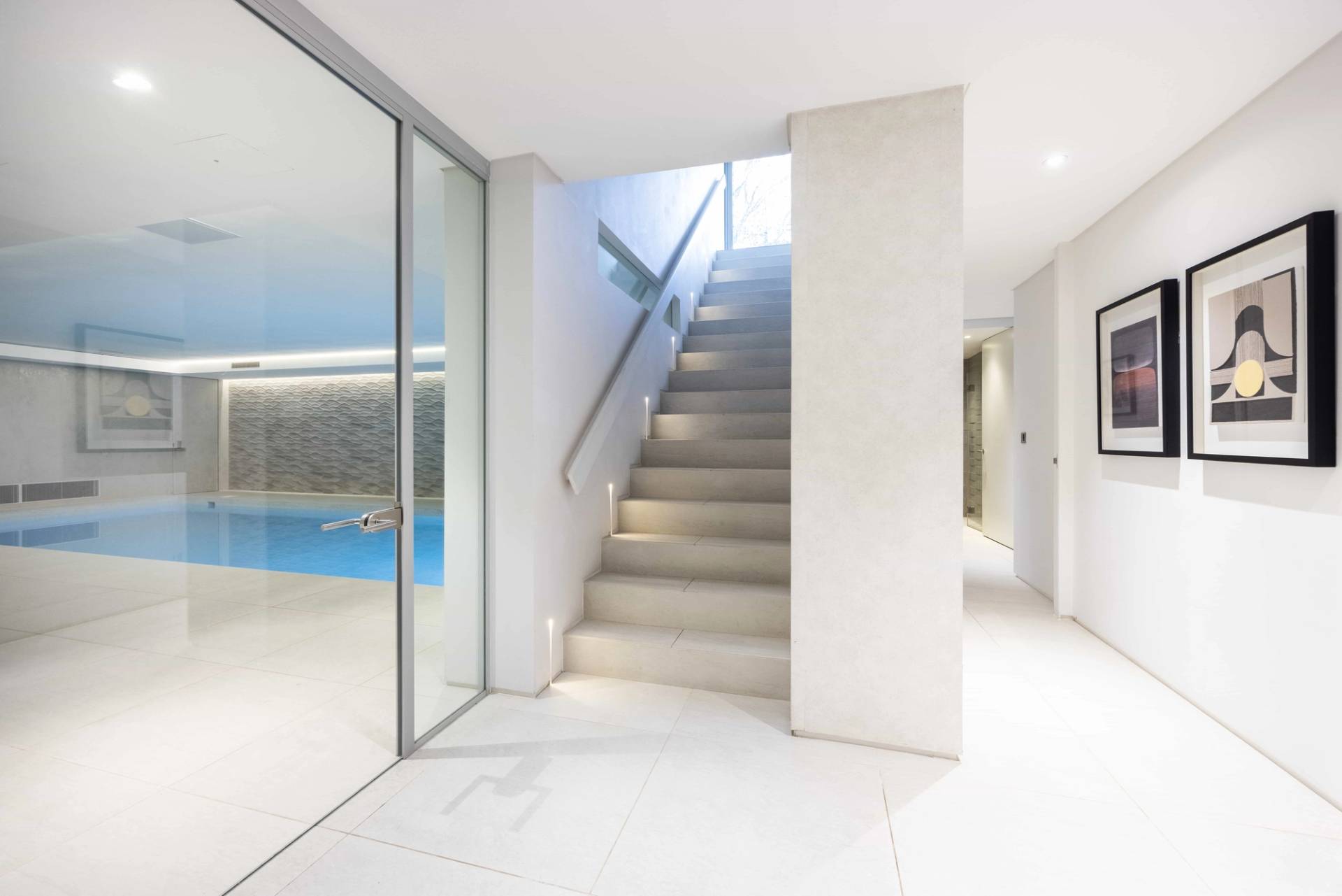 Minimalist interior staircase leading down to an indoor basement swimming pool hall, Love Locations WD7.
