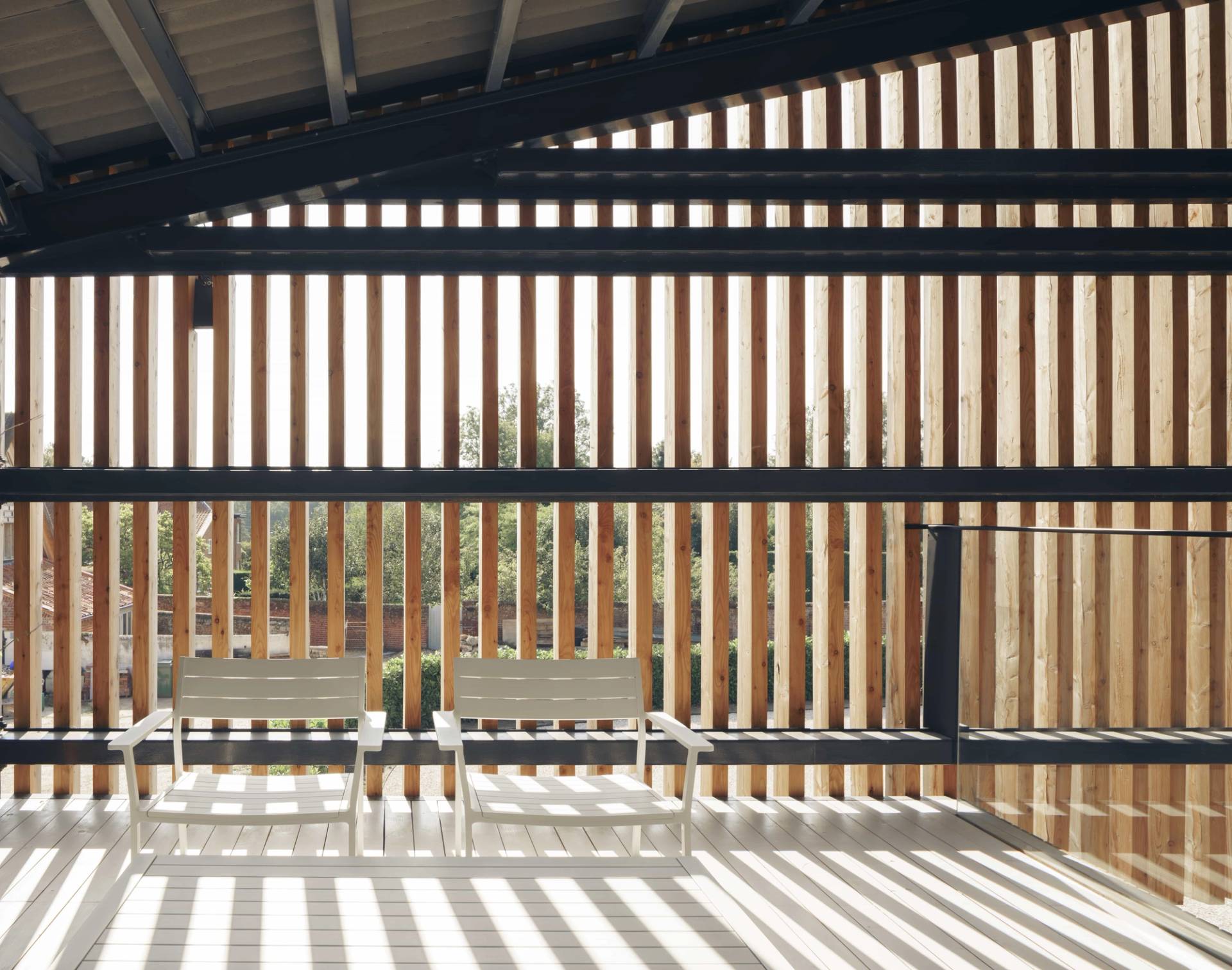 Covered outdoor terrace with vertical timber slatted sun screen casting geometric shadows, Love Locations NR9.