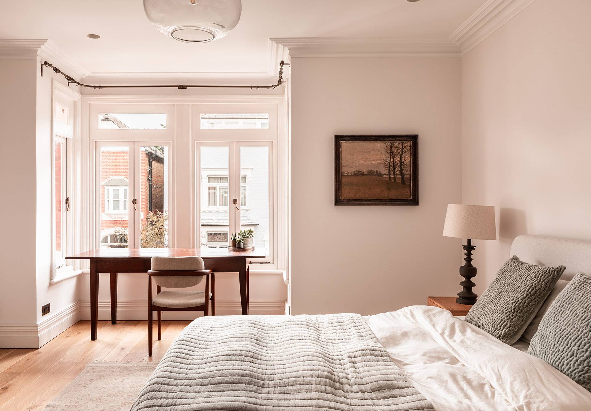 Serene bedroom layout with a period fireplace, wooden floors, and sash windows framing street views, ideal for luxury hotel-style shoots, Love Locations.