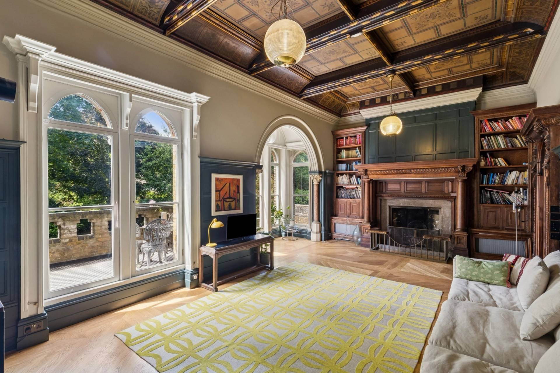 Elegant library lounge shoot venue in Hampstead NW3 through Love Locations, displaying tall arched windows, coffered ceiling, and wooden surround fireplace.