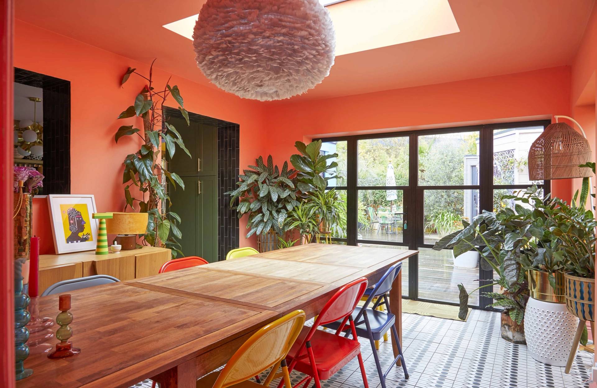 Coral orange dining extension featuring full-width black glass doors opening onto garden decking, Love Locations SE6.