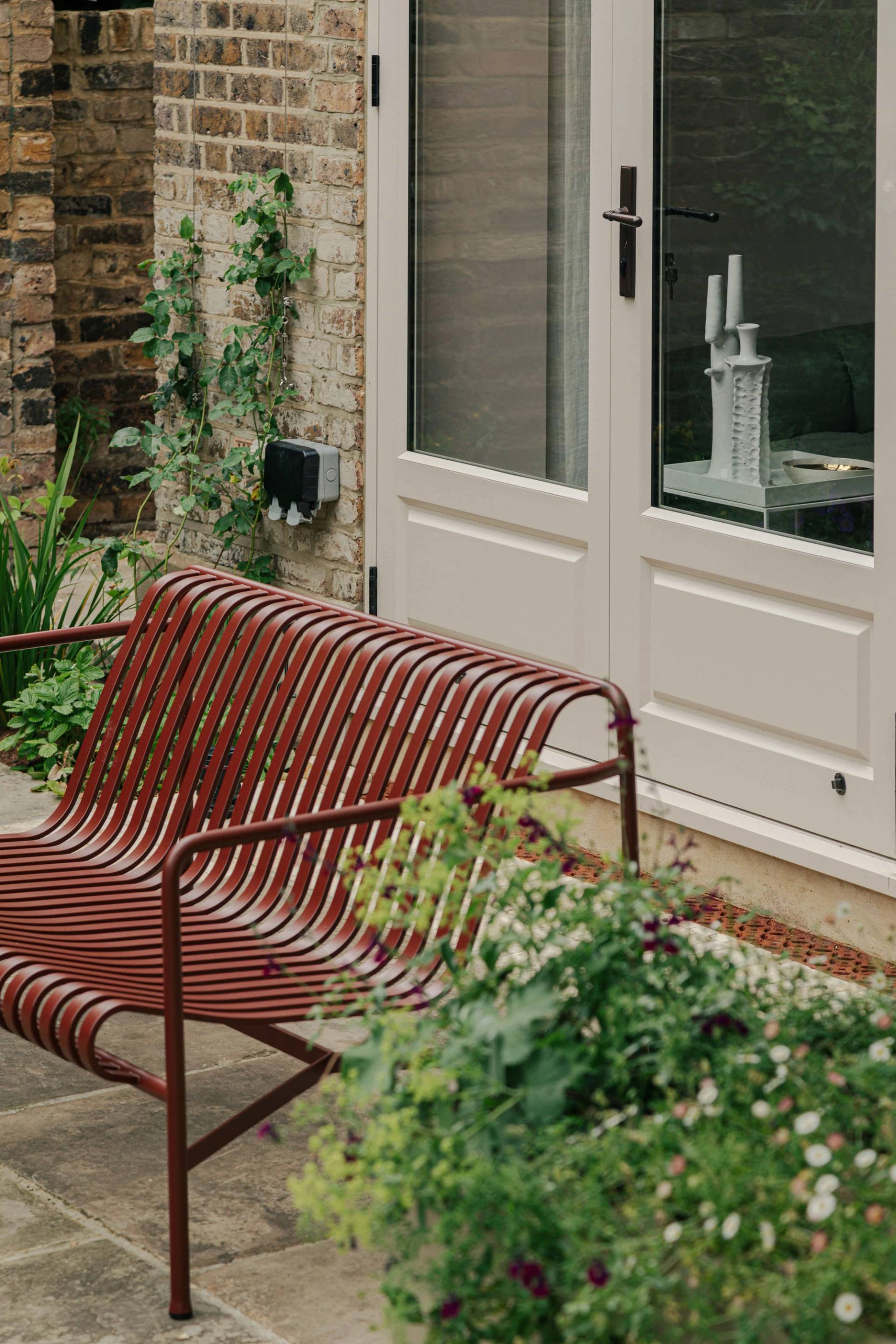 Cozy garden bench corner set on a stone paved patio surrounded by climbing plants, Love Locations.