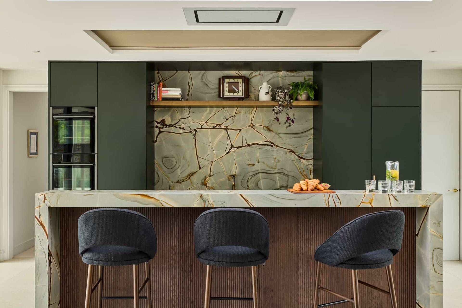 Luxury kitchen island featuring green marble waterfall counters and sleek dark cabinetry in a Surrey KT22 location property, Love Locations.