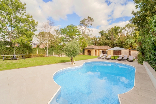 Curved outdoor swimming pool surrounded by manicured lawns and mature trees, Love Locations RM11.