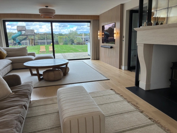 Modern sitting room shoot location in Essex CM4 through Love Locations, highlighting a minimalist stone fireplace, neutral area rug, and wide glass doors opening to outdoor greenery.