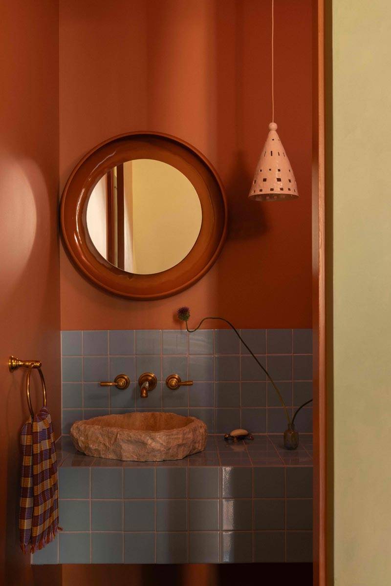 Terracotta-toned powder room photoshoot venue in Boerum Hill Brooklyn NY 11217 by Love Locations, featuring a circular mirror and stone vessel sink.