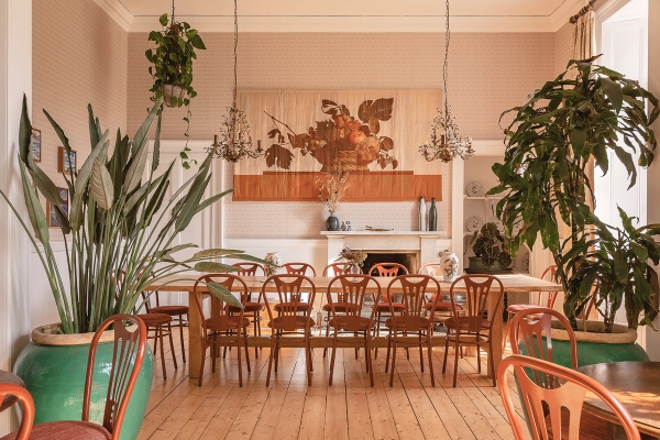 Banqueting dining hall set with a long wooden table, wooden chairs, and hanging ceiling plants, Love Locations KY15.