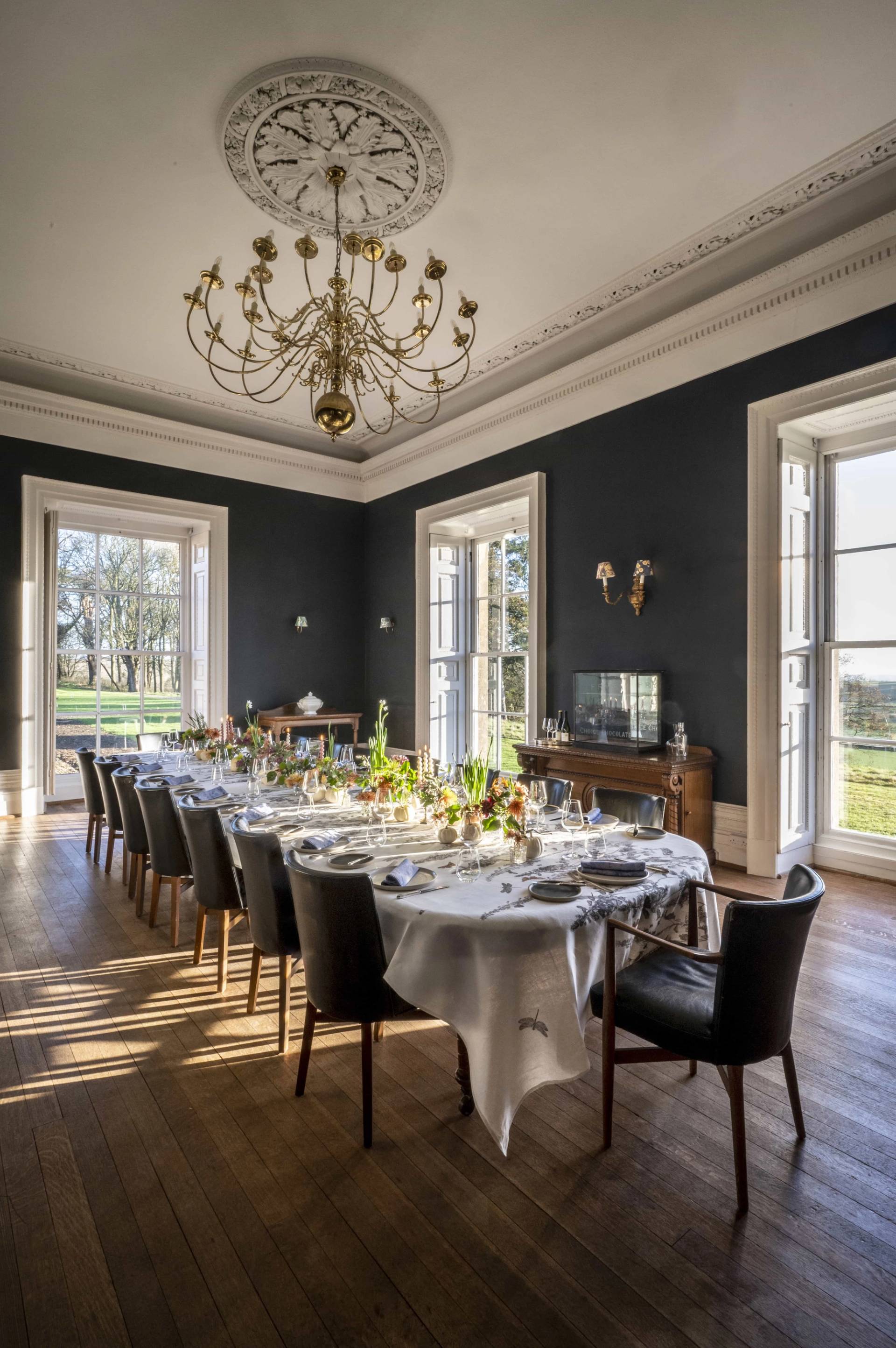Formal dark navy dining room set with a long banquet table, white tablecloth, and crystal chandelier, ideal for luxury event and food commercial shoots, Love Locations.