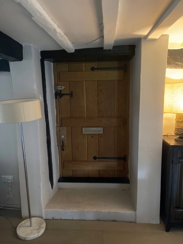 Heavy antique wooden front door with traditional iron hardware and bolt locks inside a historic Tudor cottage entryway, Love Locations RG9 6QD.