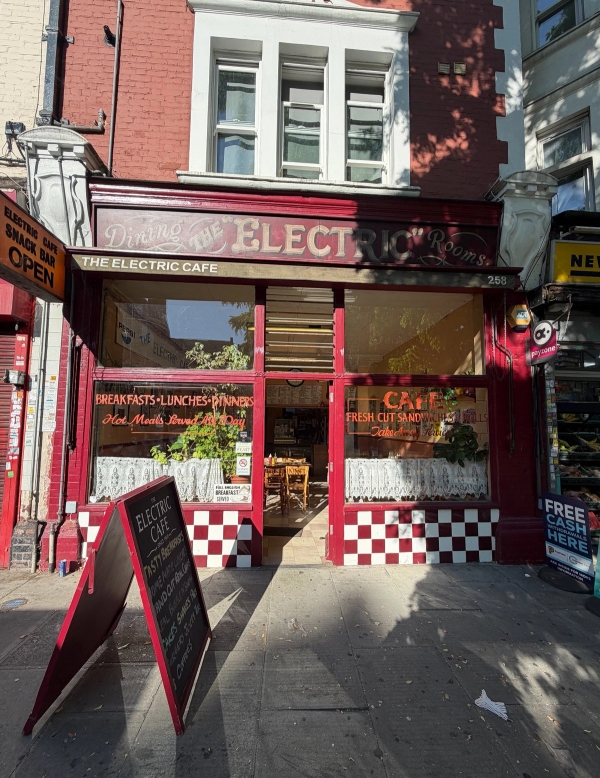 Exterior front view of a retro red shopfront cafe location with A-board sign and checkered window trim in Tulse Hill, Love Locations SE27.