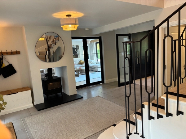 Welcoming reception hallway shoot location in Essex CM4 from Love Locations, featuring a cozy fireplace setup, neutral rug, circular mirror, and statement lighting.