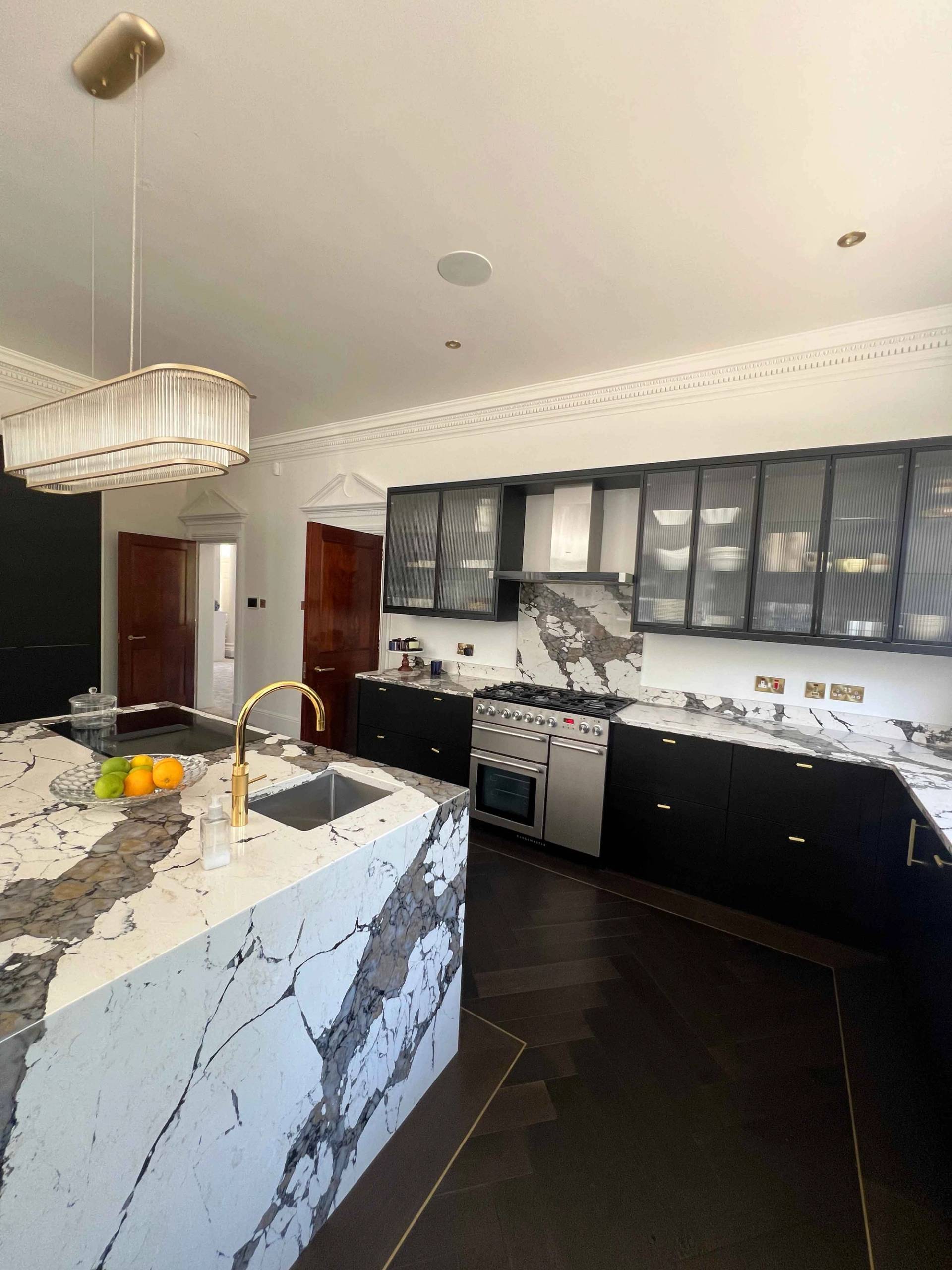 Modern kitchen island featuring dramatic dark veined marble waterfall countertops and integrated gas hob, Love Locations BR7.