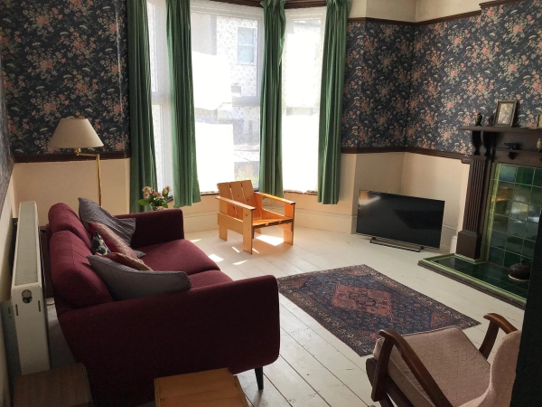 Eclectic living room shoot location in Croydon, SE25 featuring dark floral wallpaper, painted floorboards, and period sash windows, ideal for retro fashion editorials via Love Locations.