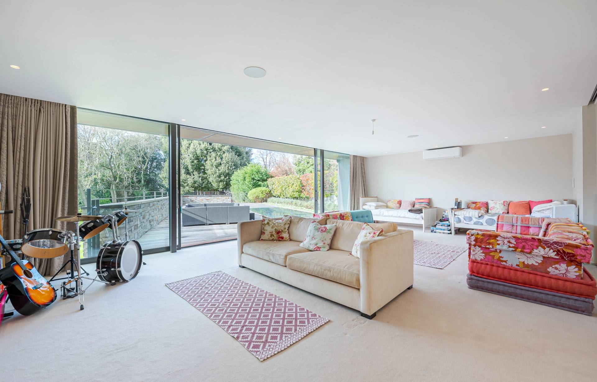 Spacious second living room or media lounge with cream sofas and full-height glass doors opening to a terrace, Love Locations KT2.