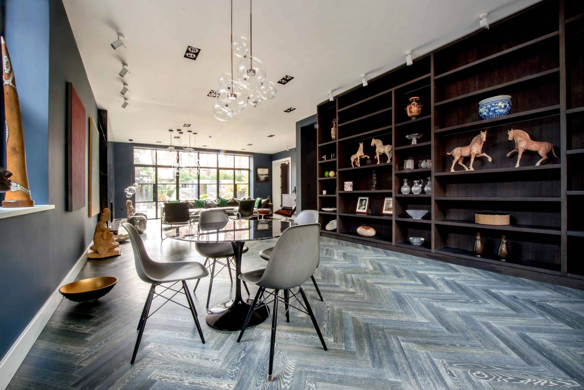 Modern home library and informal seating zone with herringbone wood floors and designer pendant lights in Belsize Park, Love Locations.