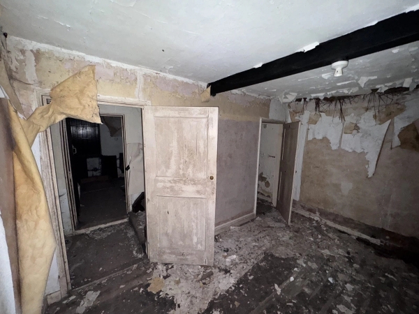 Atmospheric view looking through a peeling white wooden door inside a derelict Victorian cottage, curated by Love Locations Nottingham.
