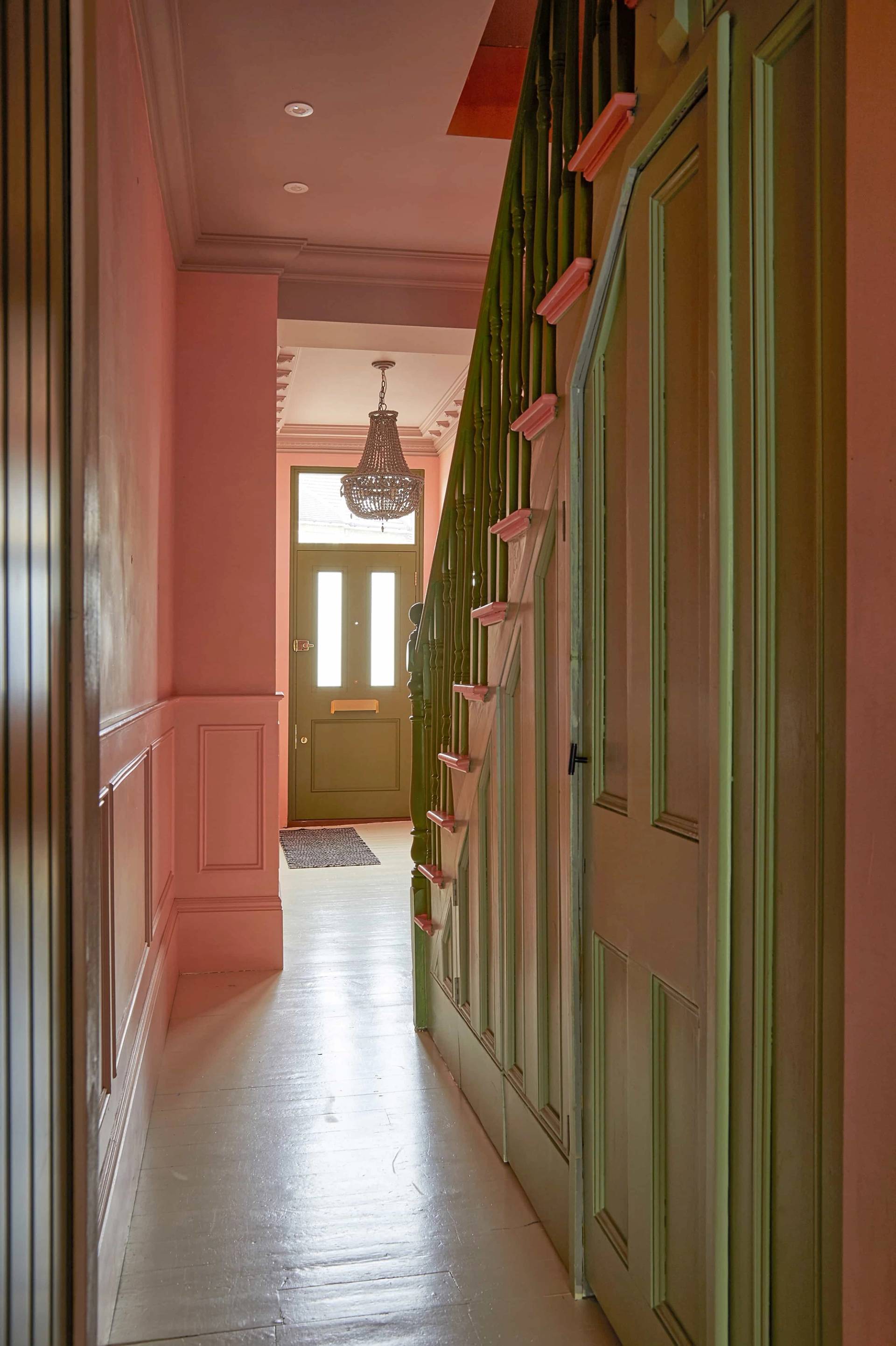 Pink and green hallway corridor view showing panelled walls and wooden staircase treads, Love Locations SE6.