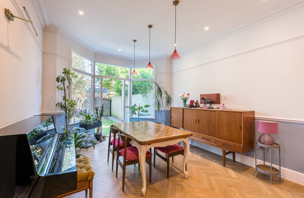 Arts and Crafts style dining room location with a mid-century wooden sideboard and large glass doors to the garden, Love Locations N11.